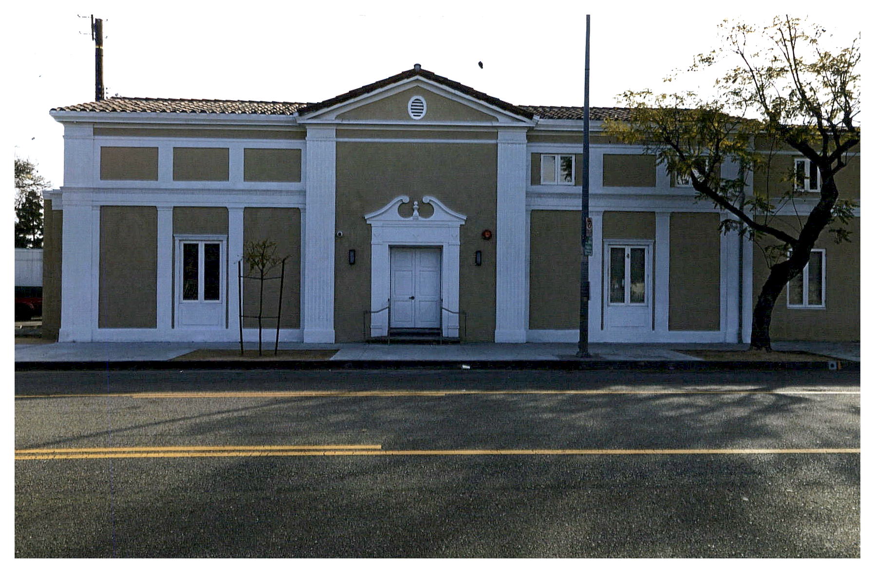 After: street facade of Angelus with beige stuccoed walls and white Federalist trim.