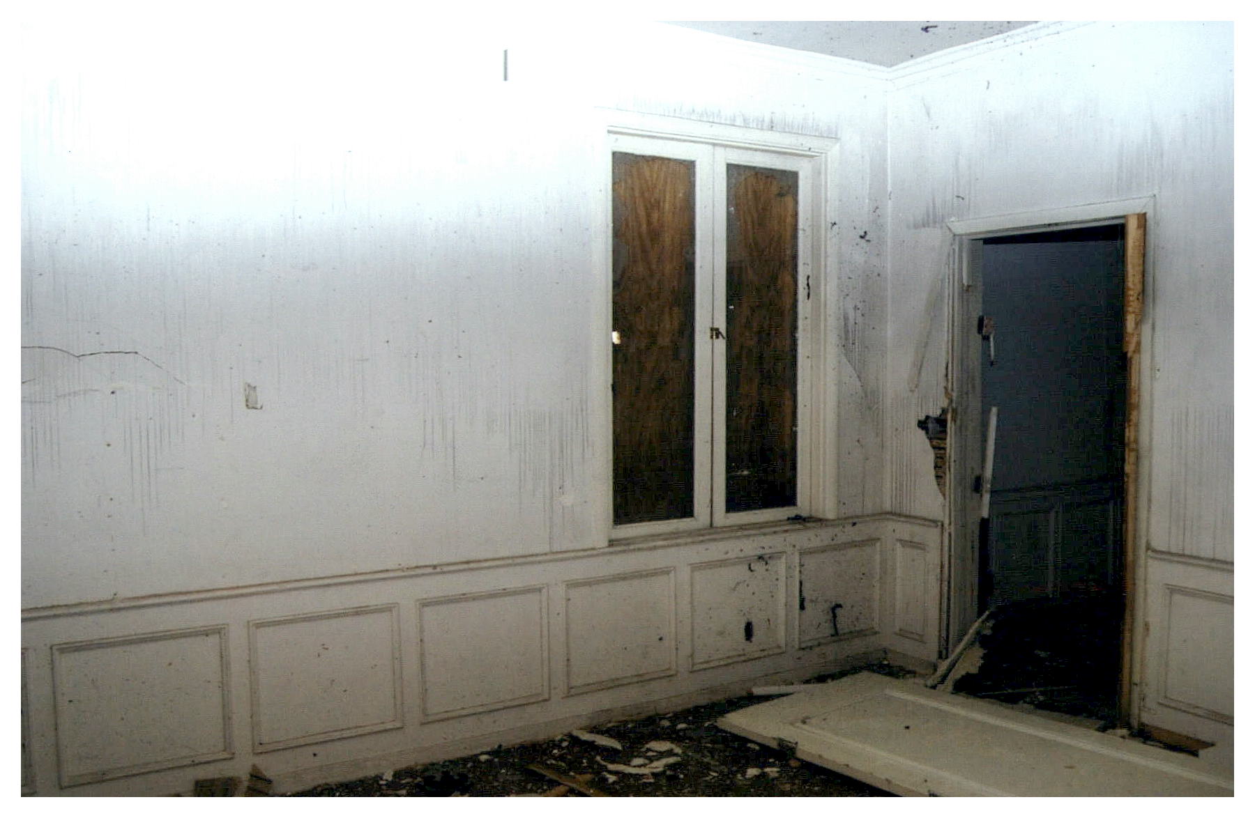 Before: same corner view with boarded up window and door lying on the floor.