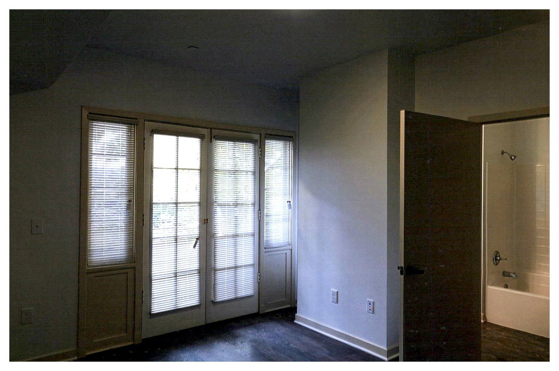 After: interior view of apartment showing entrance to bathroom and restored paired french doors and sidelites to outside.