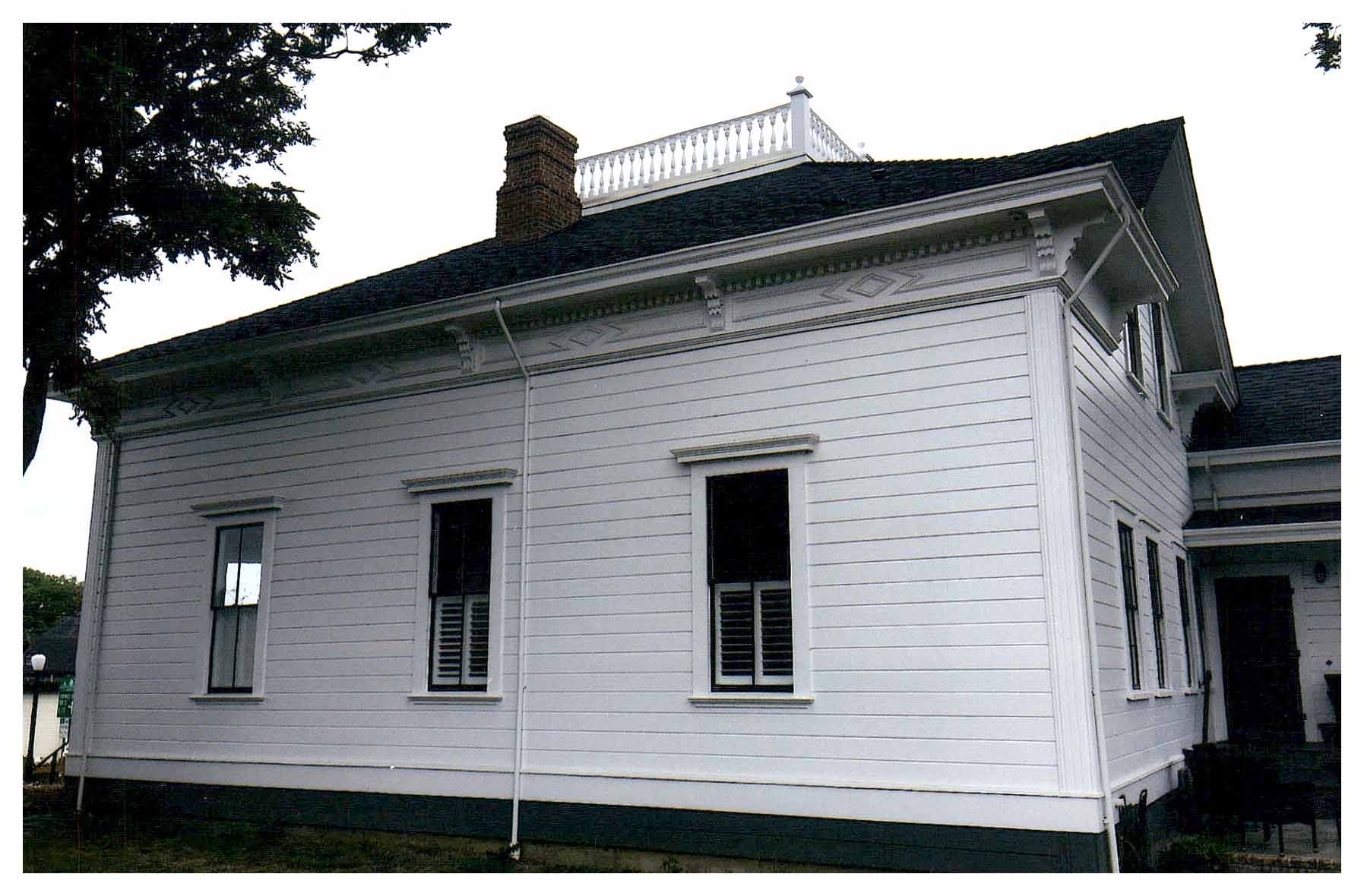 After: side facade with new white paint. Reconstructed ridge railing is visible at roof.