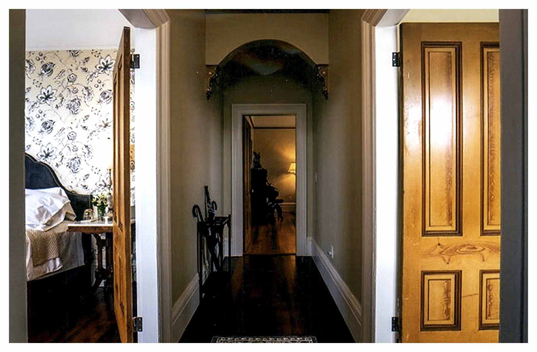After: view of other end of entrance hallway with open room doors on both sides and repaired arch above door to rooms beyond.