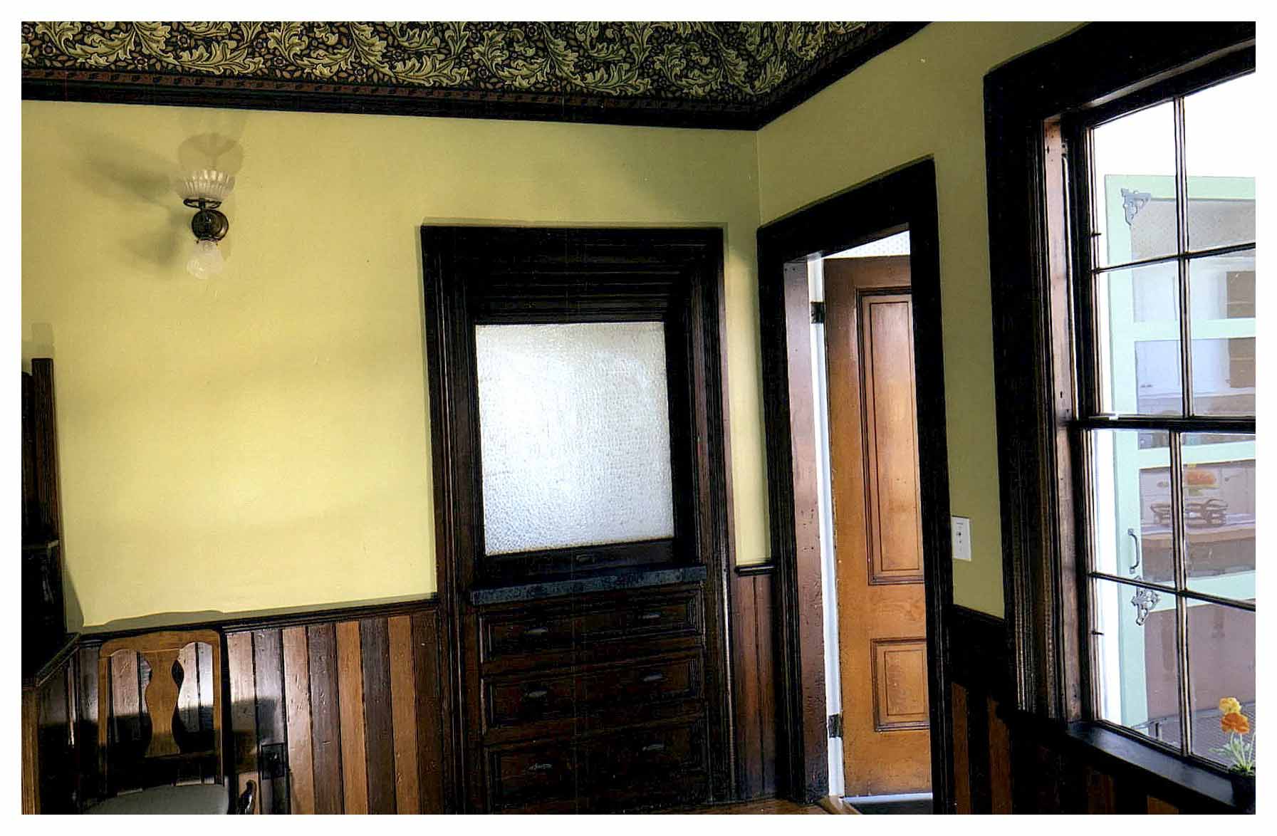 After:  corner of dining room with view of side entrance and restored door-framed drawers below and retractable upper obscure-glazed sash, revealing a counter behind.