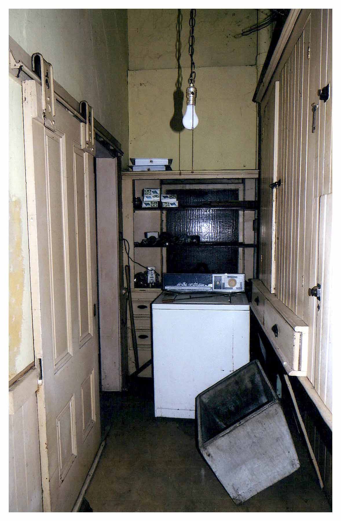 Before: unpainted pantry with shelves installed in front of sash and a washing machine.