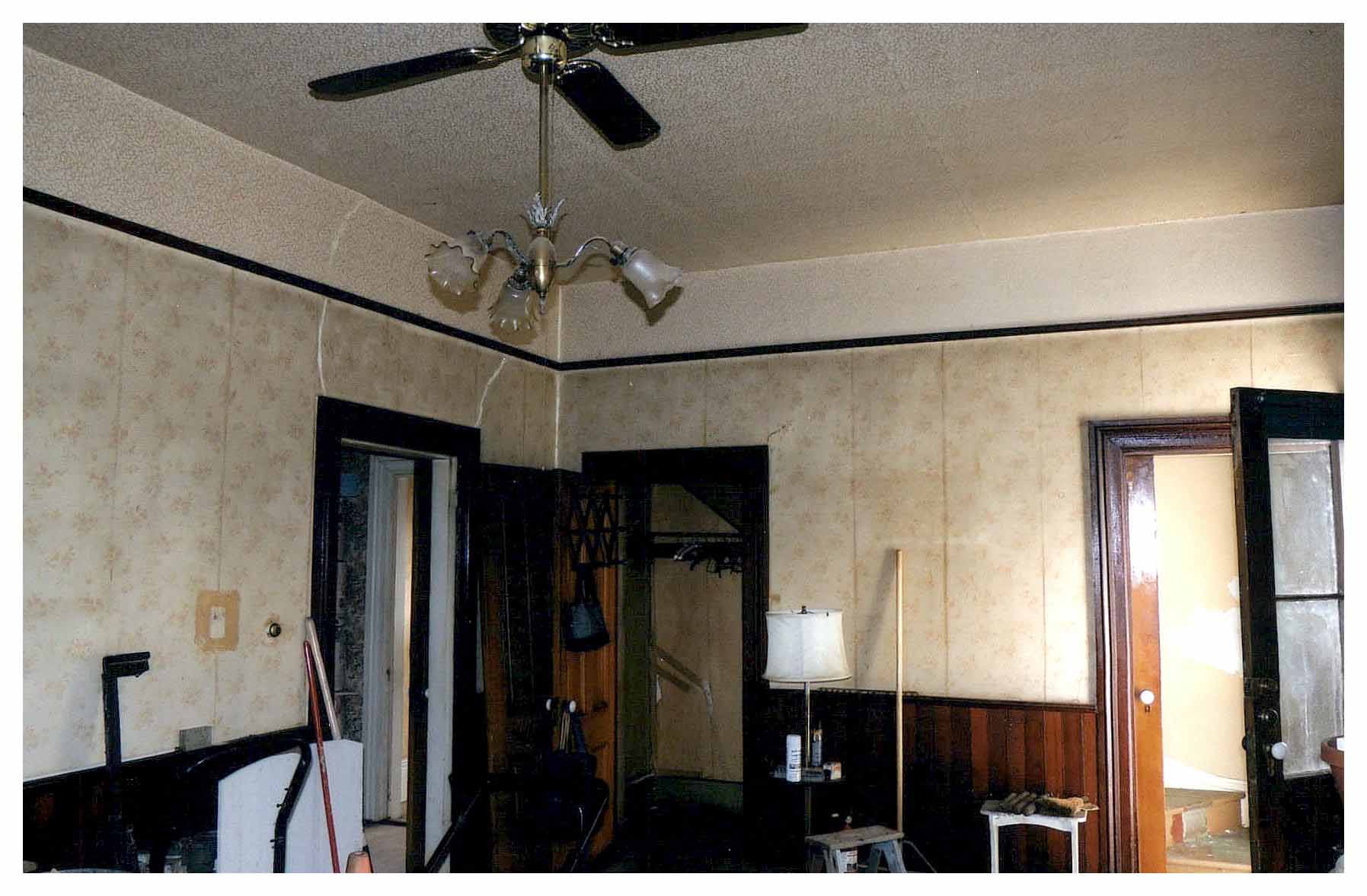 Before: dining room with old wallpaper and a ceiling fan.