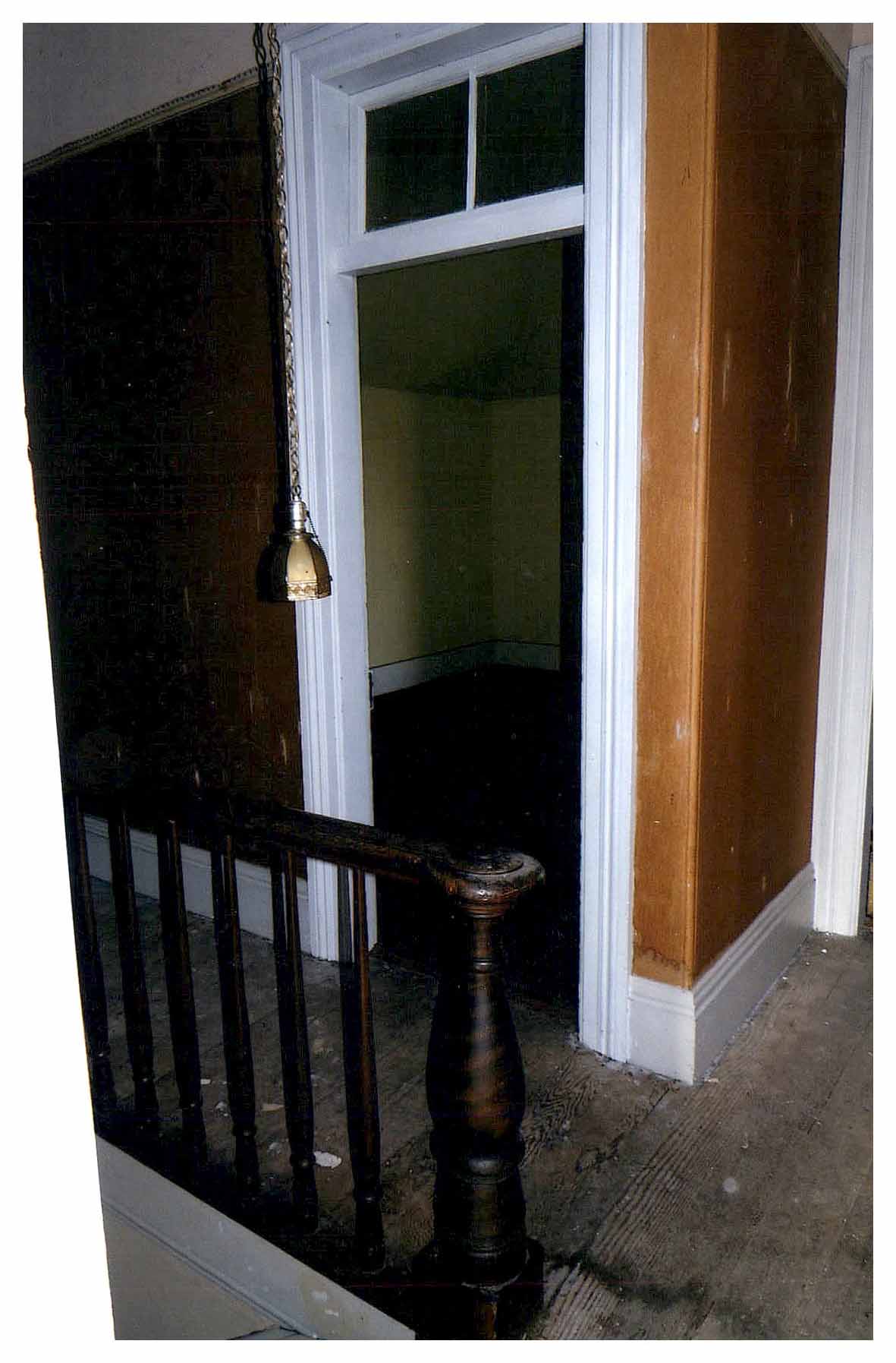 Before: same view showing worn hallway walls, unfinished wood floor and dark bedroom beyond.
