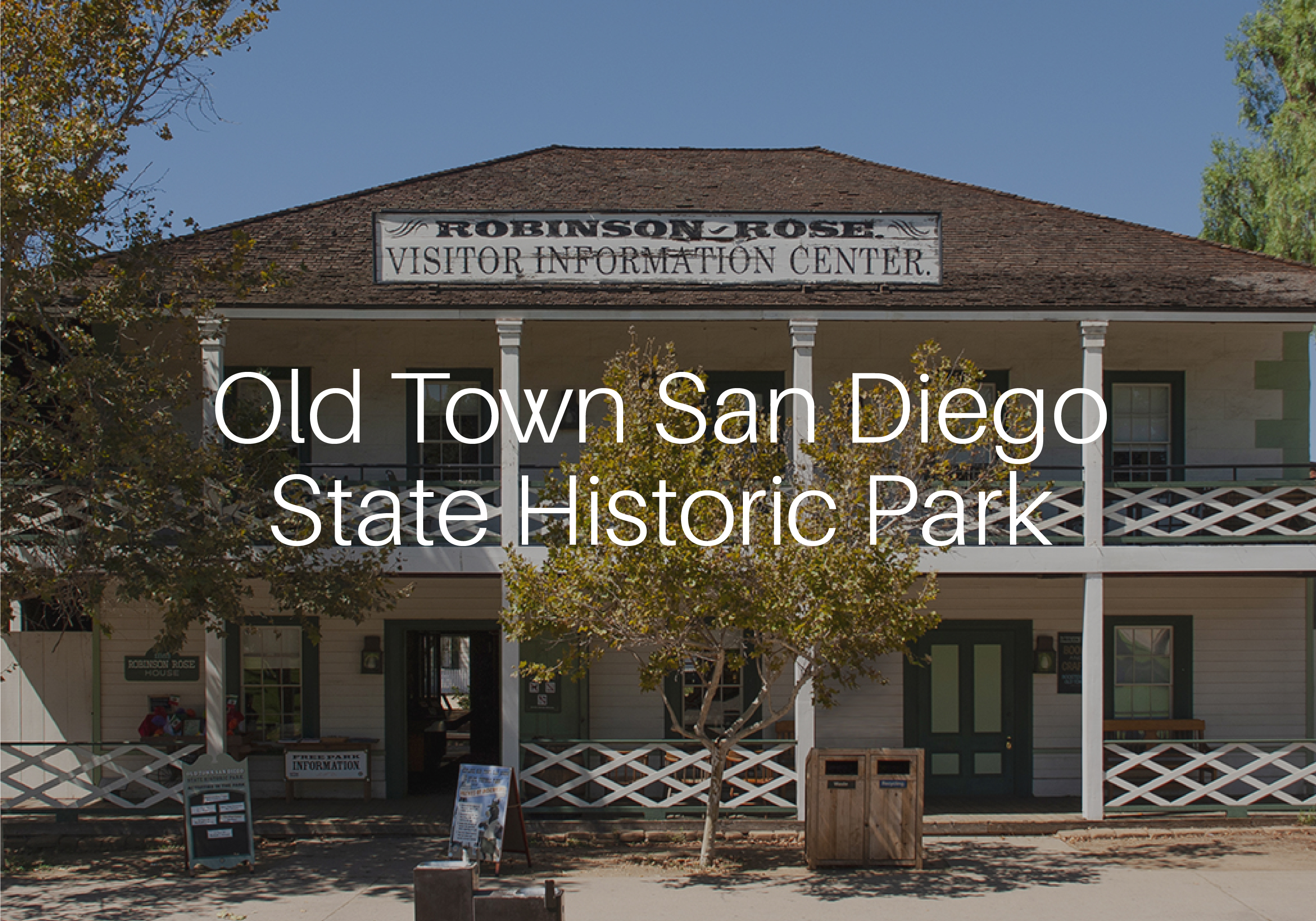 Photo of the Robinson-Rose Visitor Center in Old Town San Diego State Historic Park with the name of the park over the top of it in white san serif text. The photo is slightly dimmed to make the park name stand out.
