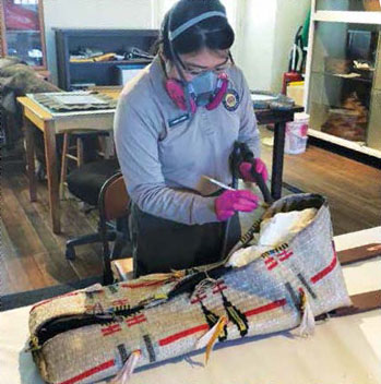 Staff Members working to conserve a Native American artifact