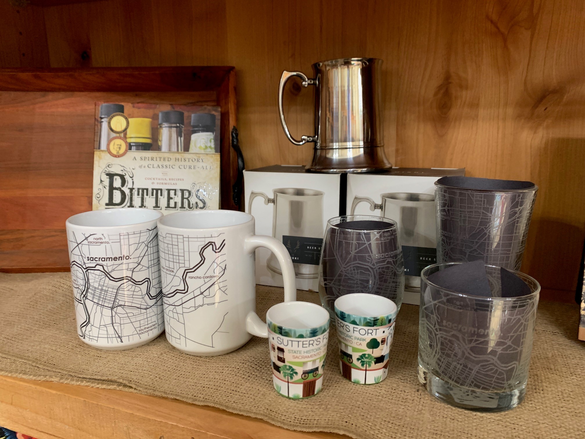 a retail display shelf featuring assorted mugs, glasses, and books