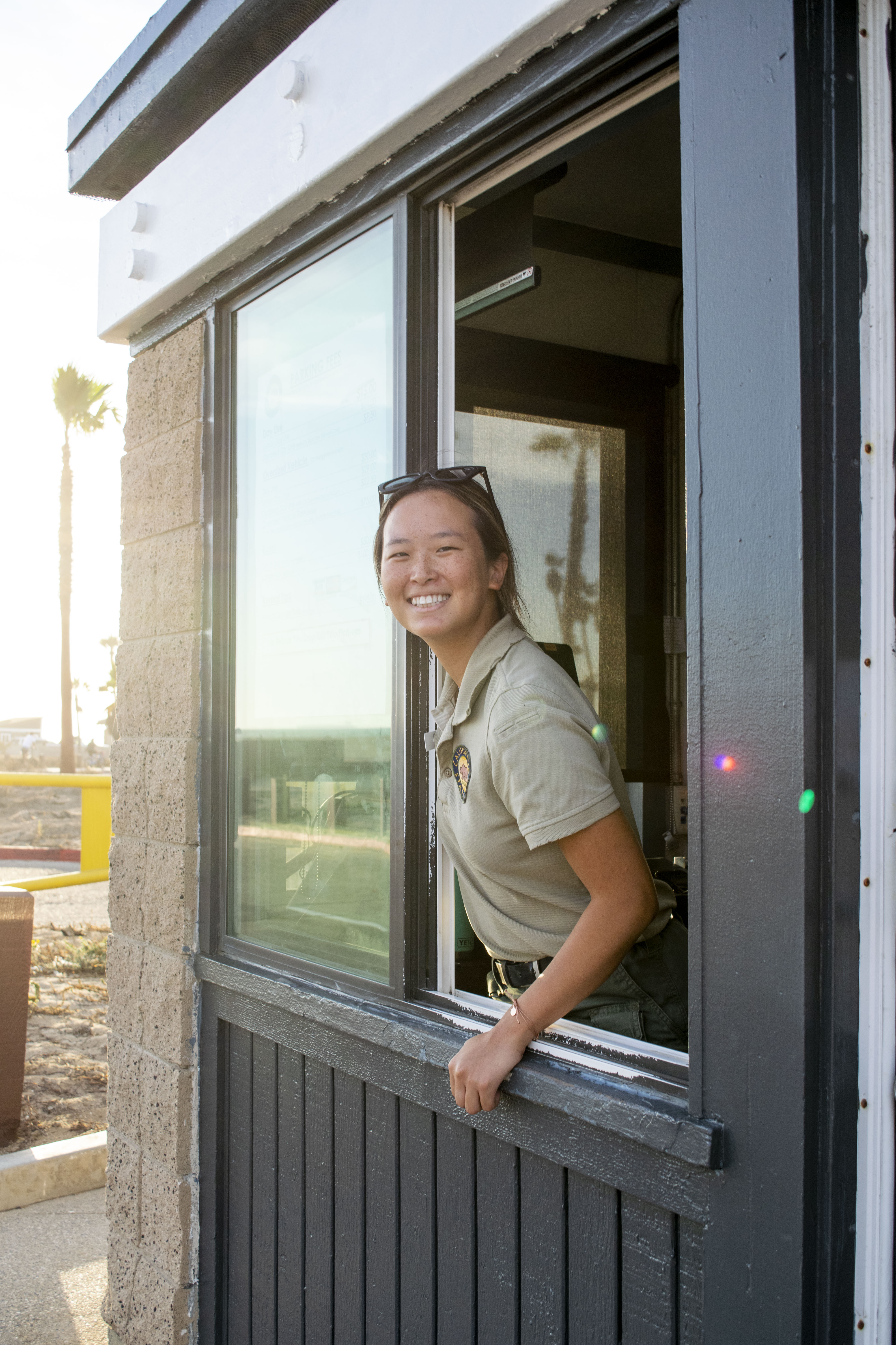 Park Aide at Huntington State Beach leans out of the kiosk window to greet guests